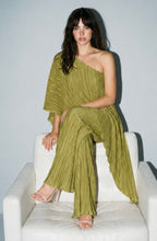 Load image into Gallery viewer, Model wearing an olive green pleated matching set featuring a one-shoulder asymmetrical flowy top and wide-leg pleated pants styled with nude heels for an elegant statement look.
