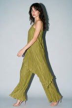 Load image into Gallery viewer, Model wearing an olive green pleated matching set featuring a one-shoulder asymmetrical flowy top and wide-leg pleated pants styled with nude heels for an elegant statement look.
