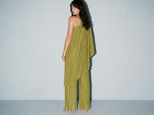 Load image into Gallery viewer, Model wearing an olive green pleated matching set featuring a one-shoulder asymmetrical flowy top and wide-leg pleated pants styled with nude heels for an elegant statement look.
