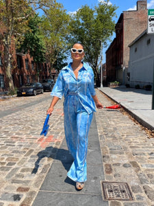 Person in a blue outfit walking on a street with buildings and trees in the background
