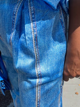 Load image into Gallery viewer, Close-up of blue denim fabric with a person&#39;s arm partially visible.
