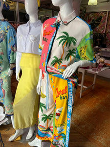 Introducing the Paradise Inn Set, featuring a printed short sleeve button-down shirt paired with chic wide-leg matching pants. Designed for comfort, the pants boast a drawstring waist. The vibrant print captures the essence of paradise, with palm trees, flamingos, and tropical colors creating an intoxicating allure. Perfect for those seeking a fun and stylish ensemble.