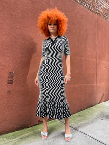Person wearing a black and white striped dress on a sidewalk.