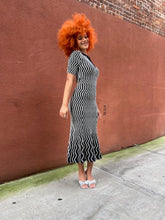 Load image into Gallery viewer, Person wearing a black and white striped dress on a red brick surface.
