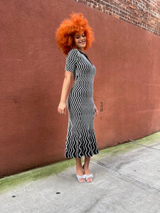Person wearing a black and white striped dress on a red brick surface.