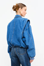 Load image into Gallery viewer, Model wearing an indigo denim bomber jacket with structured shoulders, zip-front closure, elastic hem, and gathered cuffs against a white background.
