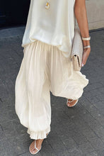 Load image into Gallery viewer, Ivory lightweight harem pants featuring a flowy crinkle texture and gathered cuffs, styled for vacation, resort, and coastal-inspired outfits.
