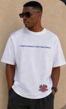 Load image into Gallery viewer, Model wearing an oversized white premium graphic T-shirt featuring the phrase "Largest Comeback in Finals History" with a small Glam Expressway logo detail, styled with black shorts and sunglasses.
