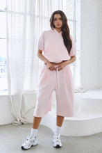 Load image into Gallery viewer, Light pink fleece Bermuda shorts with front pintuck detailing, elastic drawstring waistband, side pockets, relaxed fit, and soft stretch fabric.
