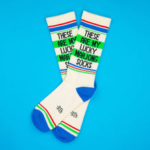 Load image into Gallery viewer, Pair of cream Lucky Mahjong gym crew socks featuring “These Are My Lucky Mahjong Socks” lettering, green, red and blue athletic stripes, and contrasting bright blue heels and toes on a blue background.
 
