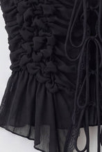 Load image into Gallery viewer, Black sleeveless ruched lace tie top featuring intricate floral ruching, adjustable front ties and feminine peplum hem on white background.
