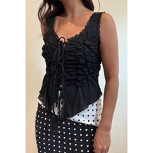Load image into Gallery viewer, Model wearing a black sleeveless ruched lace tie top with intricate front ruching, lace trim and adjustable tie front paired with a polka dot skirt.
