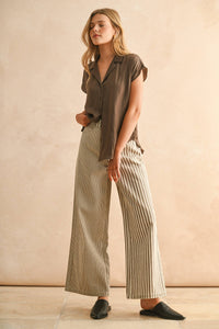Woman wearing a brown shirt and Glam Expressway's Mixed striped pants against a beige background