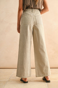 Person wearing beige mixed striped wide-leg pants against a beige background