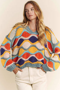 Woman wearing a colorful patterned sweater against a neutral background