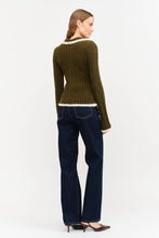 Load image into Gallery viewer, Model wearing olive green fitted double-zip knit top with ivory fuzzy trim, long sleeves, and pointed collar, styled with dark-wash wide-leg jeans.”
