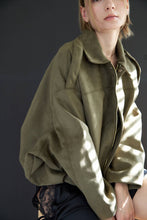 Load image into Gallery viewer, Person wearing a green jacket against a dark background
