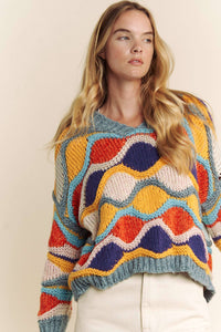 Woman wearing a colorful patterned sweater against a plain background