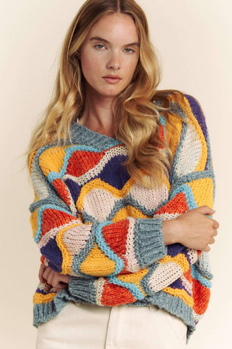 Woman wearing a colorful patterned sweater against a plain background