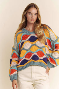 Woman wearing a colorful patterned sweater against a plain background