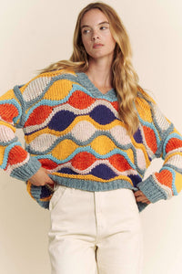 Woman wearing a colorful patterned sweater against a plain background