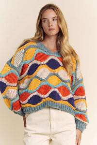 Woman wearing a colorful patterned sweater against a plain background