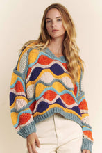 Load image into Gallery viewer, Woman wearing a colorful patterned sweater against a plain background
