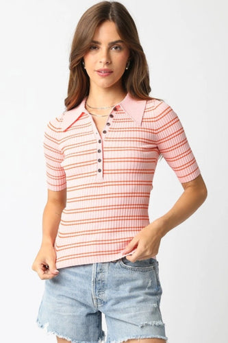 Woman wearing a pink and orange striped polo shirt with denim shorts on a white background