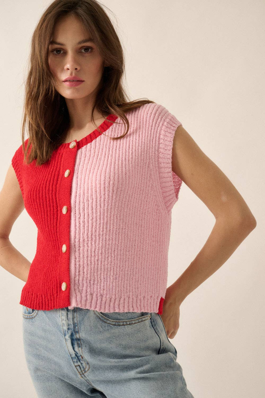 Woman wearing a red and pink ribbed knit cardigan on a plain background
