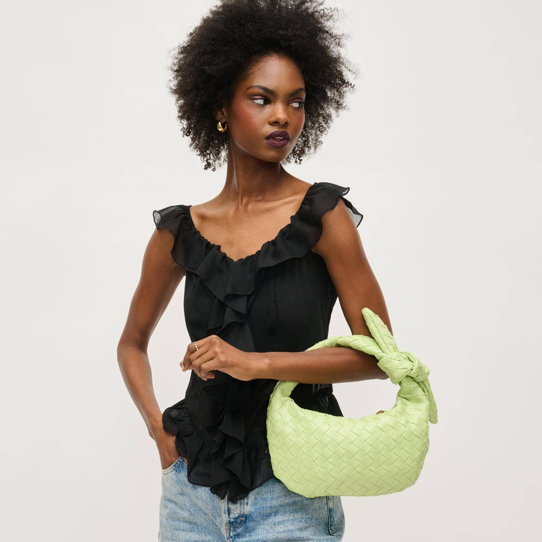 Woman holding a pistachio green woven handbag against a plain background