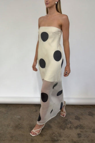 Woman wearing a chic Glam Expressway strapless dress with black polka dots against a plain background