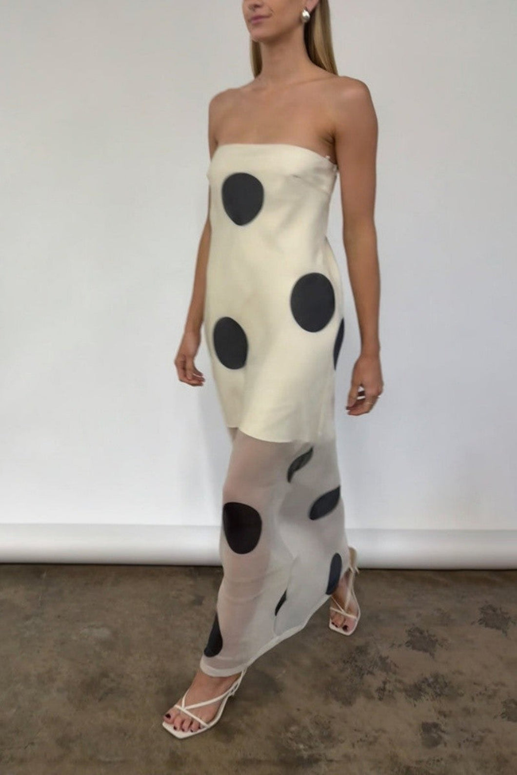 Woman wearing a chic Glam Expressway strapless dress with black polka dots against a plain background