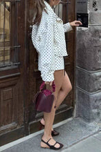 Load image into Gallery viewer, White cropped jacket with black polka dot print, featuring a high collar, long sleeves, and adjustable drawstring hem.
