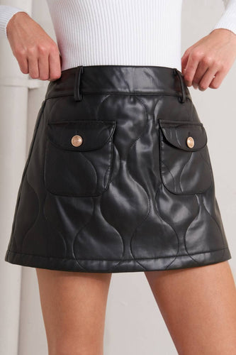 Black leather skort with gold buttons worn by a person on a white background