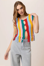 Load image into Gallery viewer, Model wearing a colorful striped knit tank top featuring vibrant vertical rainbow stripes, sleeveless design, fringe hem detailing, and functional front buttons; paired with light-wash drawstring jeans for a fun, retro-inspired summer look. Ideal for festivals and warm-weather style.
