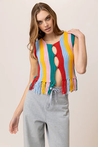 Model wearing a colorful striped knit tank top featuring vibrant vertical rainbow stripes, sleeveless design, fringe hem detailing, and functional front buttons; paired with light-wash drawstring jeans for a fun, retro-inspired summer look. Ideal for festivals and warm-weather style.