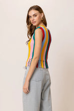 Load image into Gallery viewer, Model wearing a colorful striped knit tank top featuring vibrant vertical rainbow stripes, sleeveless design, fringe hem detailing, and functional front buttons; paired with light-wash drawstring jeans for a fun, retro-inspired summer look. Ideal for festivals and warm-weather style.
