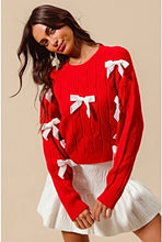 Load image into Gallery viewer, Add a playful pop of color to your wardrobe with our Cherry Red Cable Knit Sweater, adorned with delicate white ribbon bow appliqués! This cozy yet statement-making sweater features a classic cable knit design in a bold red hue, with charming white bows adding a whimsical touch. Perfect for pairing with jeans or a skirt, this sweater will keep you warm and stylish all season long. Available in sizes S to XL for the perfect fit!
