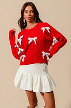 Load image into Gallery viewer, Add a playful pop of color to your wardrobe with our Cherry Red Cable Knit Sweater, adorned with delicate white ribbon bow appliqués! This cozy yet statement-making sweater features a classic cable knit design in a bold red hue, with charming white bows adding a whimsical touch. Perfect for pairing with jeans or a skirt, this sweater will keep you warm and stylish all season long. Available in sizes S to XL for the perfect fit!
