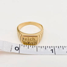 Load image into Gallery viewer, Chunky 18K gold-plated signet ring engraved with “rich bitch” and featuring ribbed detailing along the sides.
