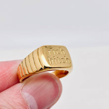 Load image into Gallery viewer, Chunky 18K gold-plated signet ring engraved with “rich bitch” and featuring ribbed detailing along the sides.
