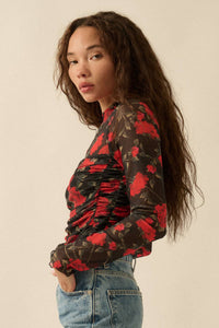 Woman wearing a floral blouse with red and black flowers on a beige background