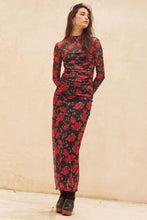 Load image into Gallery viewer, Woman wearing a red and black floral dress against a beige background

