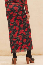 Load image into Gallery viewer, Long black skirt with red floral pattern worn by a person on a beige background
