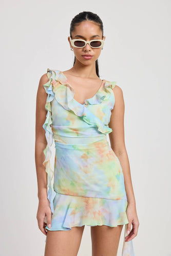Woman wearing a tie-dye dress with ruffled sleeves against a plain background