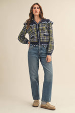 Load image into Gallery viewer, Model wearing a ruffled plaid knit cardigan with puff sleeves, scalloped trim, button-front V neckline, and contrast cable-knit yoke, styled with denim jeans.
