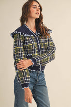 Load image into Gallery viewer, Model wearing a ruffled plaid knit cardigan with puff sleeves, scalloped trim, button-front V neckline, and contrast cable-knit yoke, styled with denim jeans.
