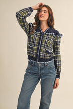 Load image into Gallery viewer, Model wearing a ruffled plaid knit cardigan with puff sleeves, scalloped trim, button-front V neckline, and contrast cable-knit yoke, styled with denim jeans.
