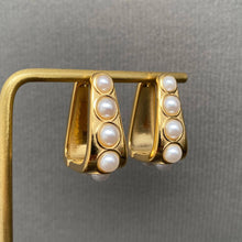 Load image into Gallery viewer, 18K gold-plated sculptural huggie earrings with four graduated white imitation pearl accents on each earring.
