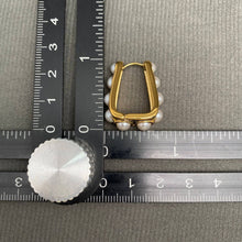 Load image into Gallery viewer, 18K gold-plated sculptural huggie earrings with four graduated white imitation pearl accents on each earring.
